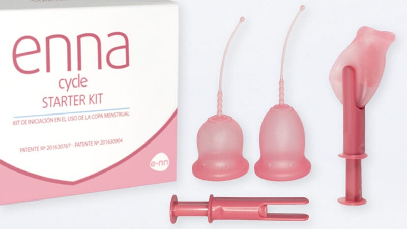 Enna Cycle menstrual cup box next to two Enna Cycle cups and an applicator. Next to that is an applicator with a cup folded and held in between two points of the applicator.